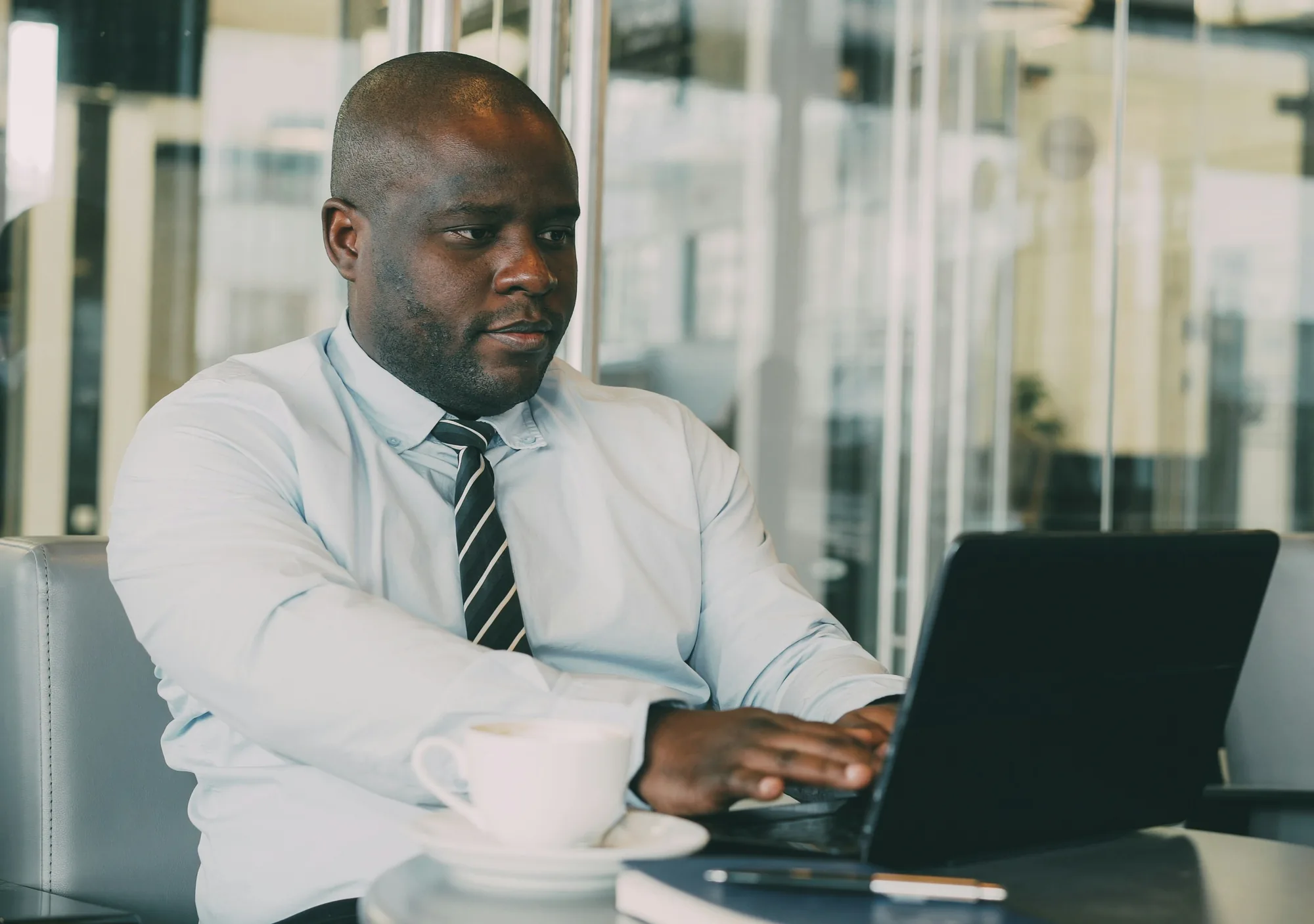 A professional working on a laptop in a bright office lounge